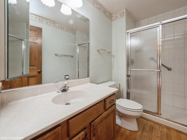 bathroom featuring vanity, a stall shower, toilet, and wood finished floors