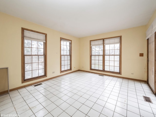empty room with light tile patterned flooring, baseboards, and visible vents