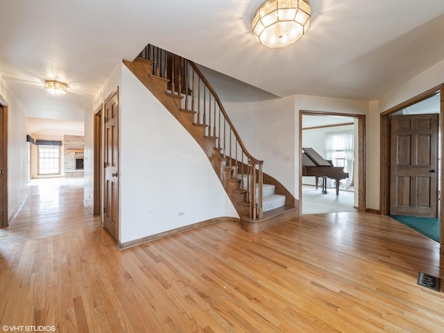 entrance foyer with visible vents, light wood-type flooring, stairway, and baseboards