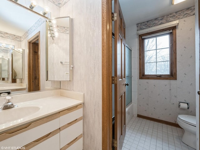 bathroom with combined bath / shower with glass door, vanity, baseboards, wallpapered walls, and toilet