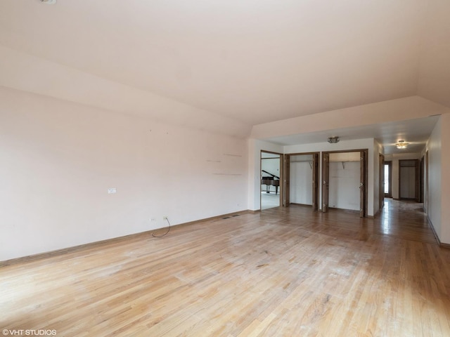 unfurnished room featuring light wood finished floors and vaulted ceiling