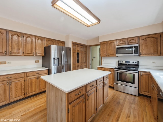 kitchen featuring a kitchen island, light wood-type flooring, brown cabinets, and appliances with stainless steel finishes