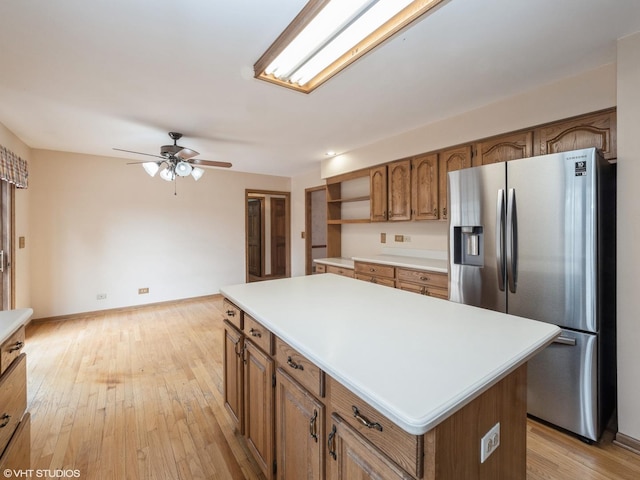 kitchen with brown cabinetry, light wood-style flooring, open shelves, a kitchen island, and stainless steel refrigerator with ice dispenser