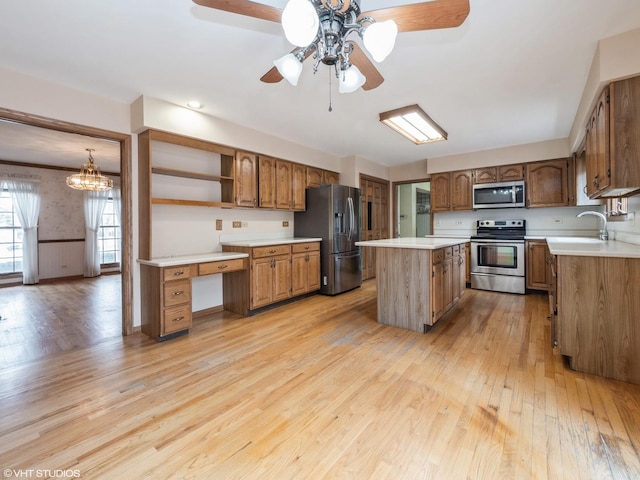 kitchen with brown cabinetry, light wood-type flooring, a wainscoted wall, and stainless steel appliances