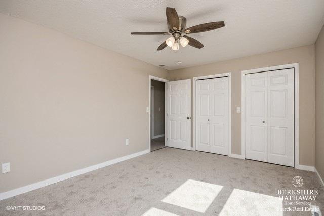 1301 W Clinton Ave, Farmer City, IL 61842 - unfurnished bedroom featuring baseboards, ceiling fan, carpet, and two closets