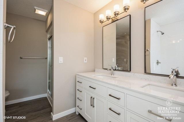 1301 W Clinton Ave, Farmer City, IL 61842 - full bath featuring double vanity, a sink, a shower with door, and wood finished floors