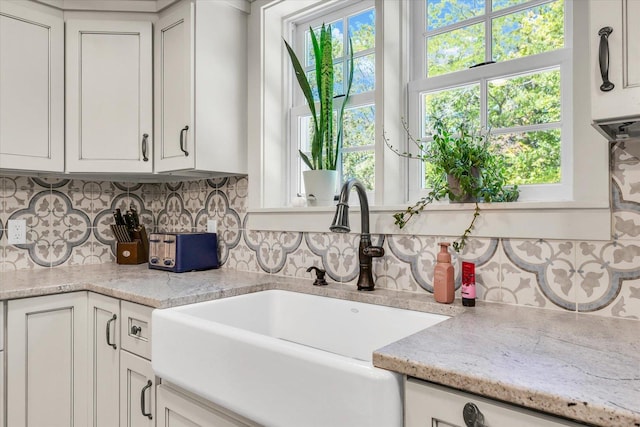 2066 County Road 125 E, Mahomet, IL 61853 - kitchen with light stone countertops, a sink, backsplash, and white cabinets