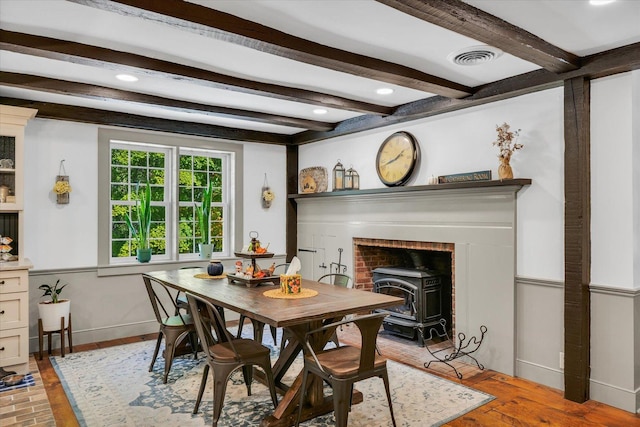 2066 County Road 125 E, Mahomet, IL 61853 - dining area with visible vents, baseboards, a wood stove, beamed ceiling, and light wood finished floors
