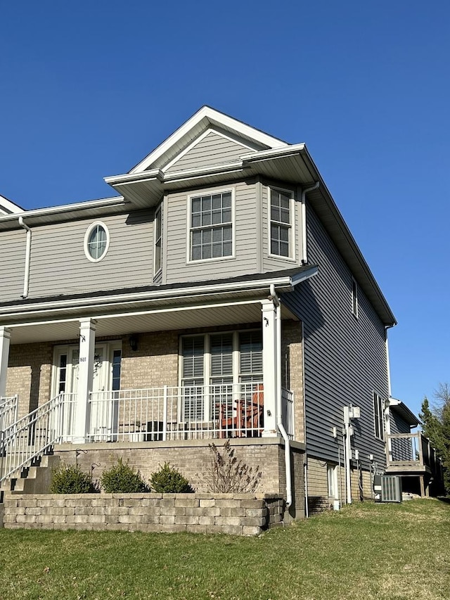 view of front of house with covered porch, central AC unit, a front lawn, and brick siding