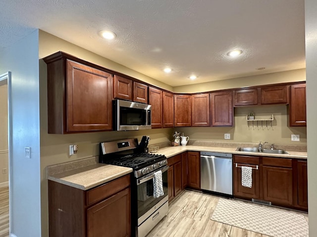 kitchen featuring a sink, light wood-type flooring, light countertops, and appliances with stainless steel finishes