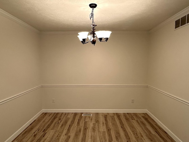 unfurnished room featuring wood finished floors, a textured ceiling, a chandelier, and visible vents