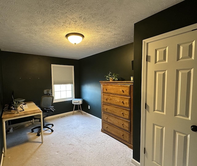 carpeted home office with baseboards, a textured ceiling, and visible vents
