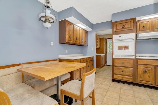 5815 E S Prairie Dr, Morris, IL 60450 - kitchen with white appliances, under cabinet range hood, light countertops, brown cabinetry, and light tile patterned floors