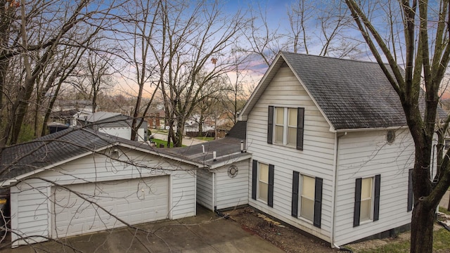view of front of property with concrete driveway, a garage, and a shingled roof