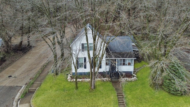 view of front of property with roof with shingles, entry steps, and a front lawn
