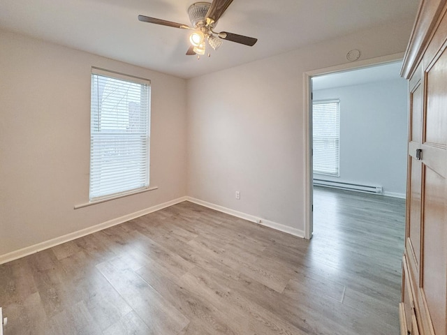 spare room featuring ceiling fan, a baseboard radiator, baseboards, and wood finished floors