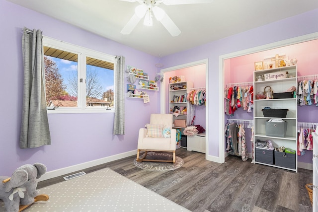 living area with baseboards, a ceiling fan, wood finished floors, and visible vents