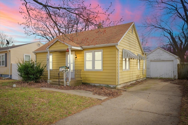 bungalow featuring an outdoor structure, driveway, a garage, a yard, and a shingled roof