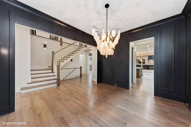 260 E Grantley Ave, Elmhurst, IL 60126 - unfurnished dining area featuring an inviting chandelier, a decorative wall, stairway, and wood finished floors