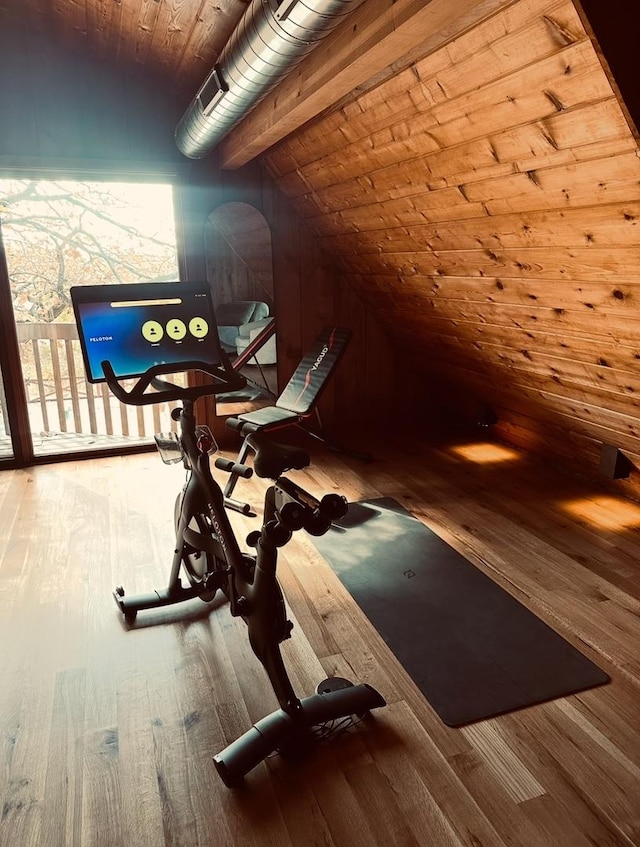 workout room featuring vaulted ceiling, wooden walls, wood finished floors, and wooden ceiling