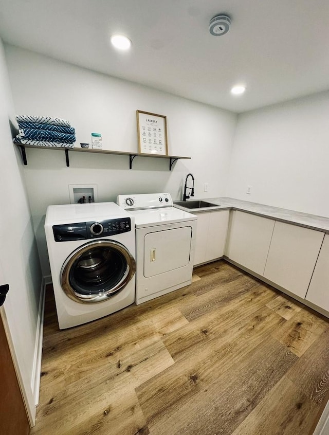 laundry room featuring recessed lighting, a sink, light wood-style flooring, cabinet space, and washing machine and dryer