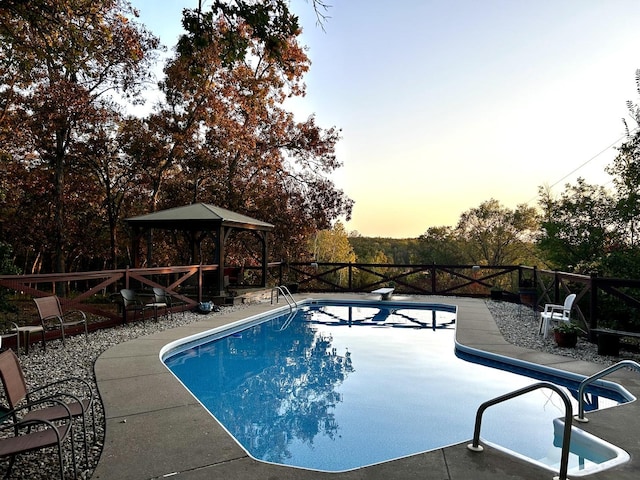 pool at dusk featuring a fenced in pool, a gazebo, and a patio area