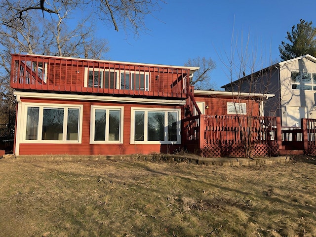 back of property featuring a wooden deck and a lawn