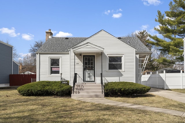 bungalow featuring a chimney, fence, a shingled roof, and a front yard