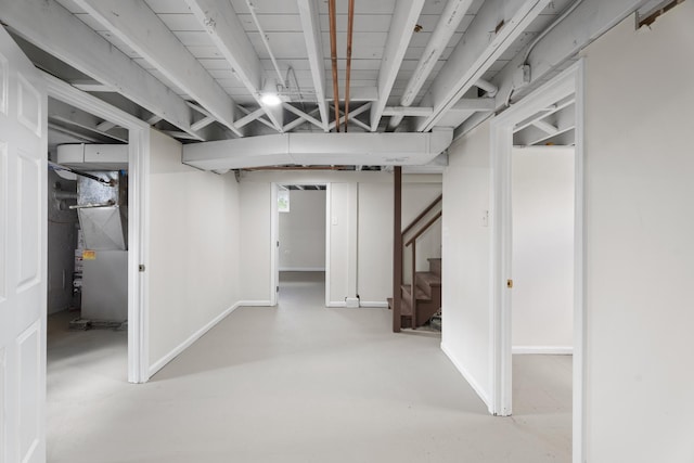 finished basement with heating unit, stairs, and baseboards