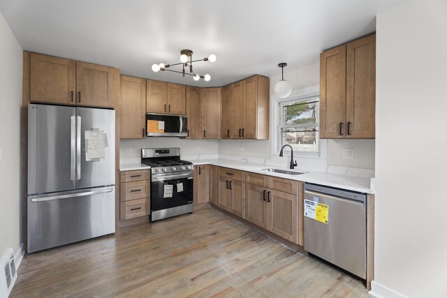 kitchen featuring light countertops, a sink, stainless steel appliances, and light wood-type flooring