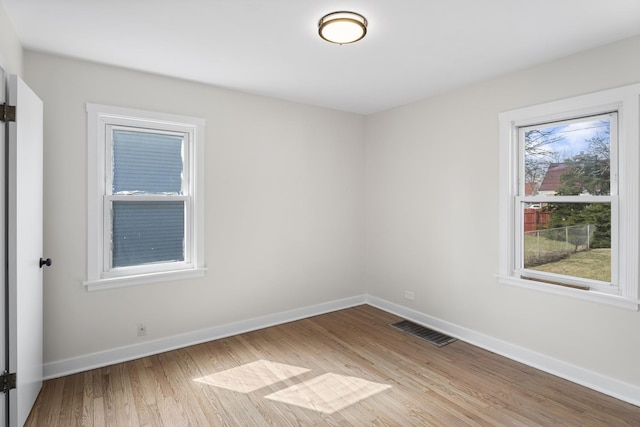empty room featuring baseboards, visible vents, and wood finished floors