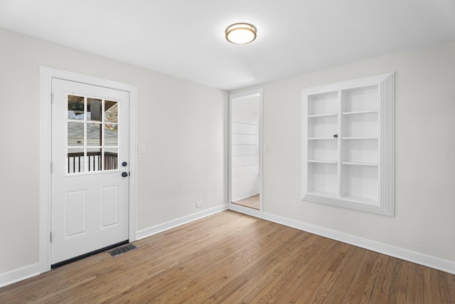 interior space featuring wood finished floors, visible vents, baseboards, and built in shelves