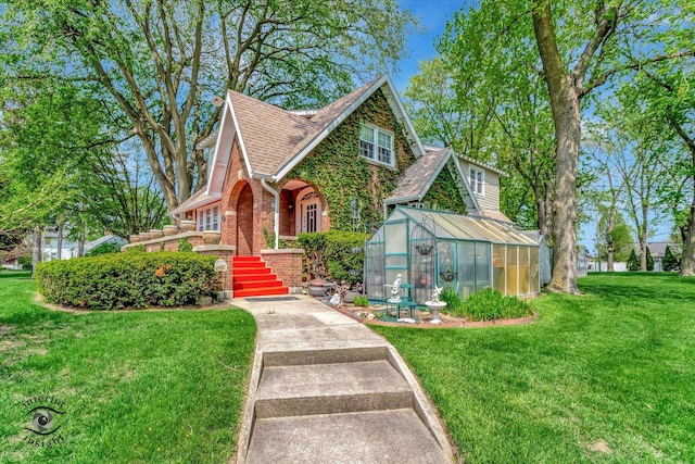 tudor house featuring an exterior structure, brick siding, and a front lawn