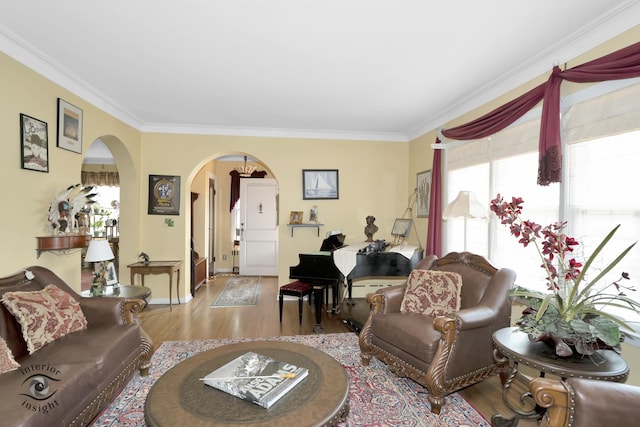 living area with arched walkways, wood finished floors, crown molding, and baseboards