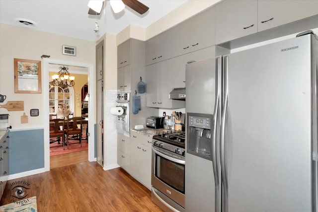kitchen featuring appliances with stainless steel finishes, a chandelier, under cabinet range hood, wood finished floors, and ceiling fan