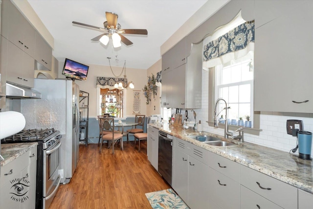 kitchen with under cabinet range hood, appliances with stainless steel finishes, a sink, a ceiling fan, and backsplash