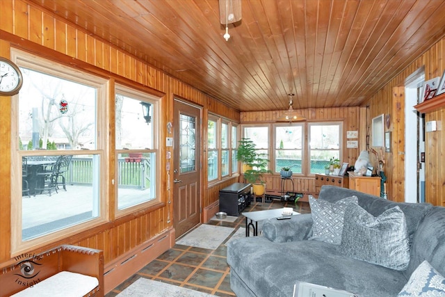 sunroom featuring wooden walls, wooden ceiling, and baseboard heating