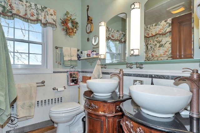 bathroom with tile walls, vanity, wainscoting, and toilet