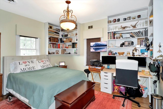 bedroom with wood finished floors and an office area