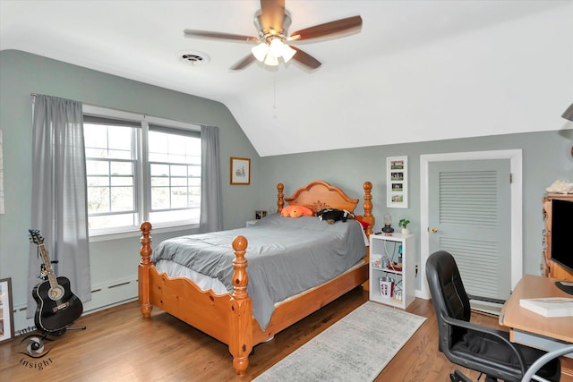 bedroom featuring lofted ceiling, a baseboard radiator, wood finished floors, and a ceiling fan