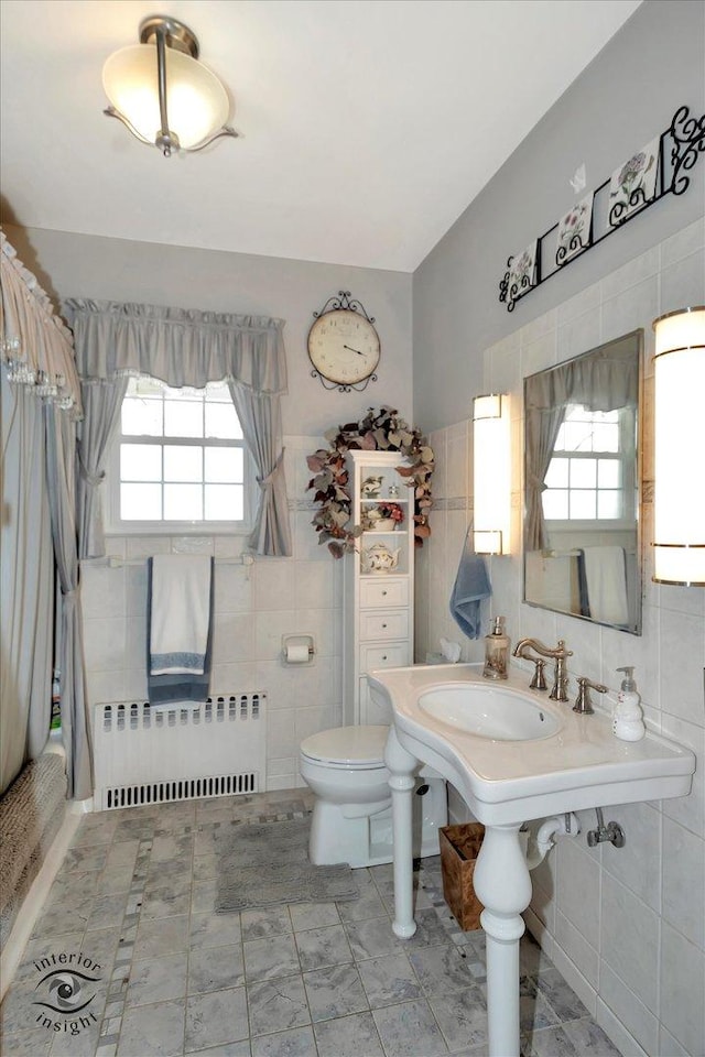 full bathroom with radiator, tile walls, plenty of natural light, and toilet