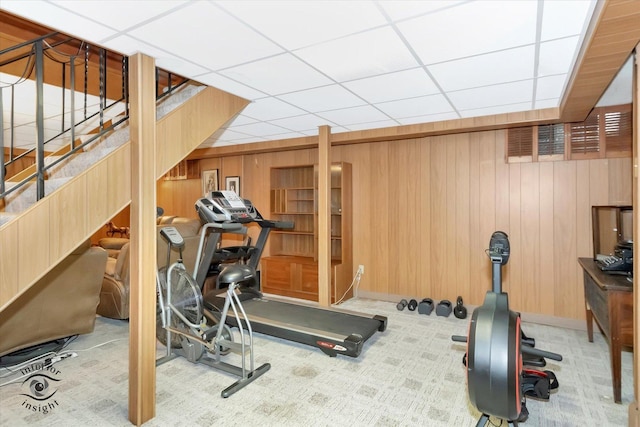 exercise area featuring wooden walls, carpet floors, baseboards, and a paneled ceiling