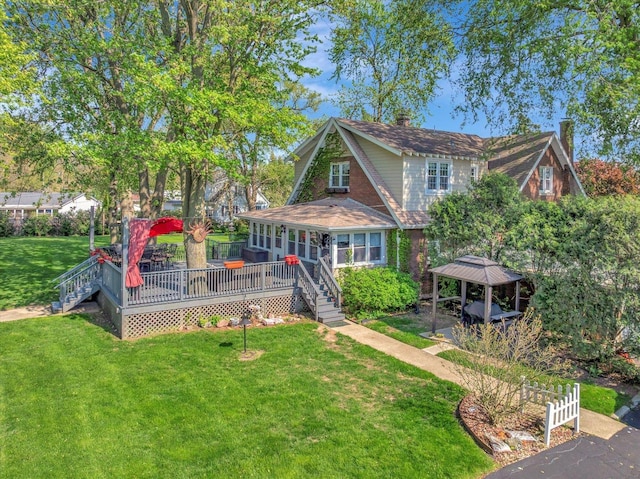 view of front facade with a gazebo, a chimney, a front yard, and a wooden deck