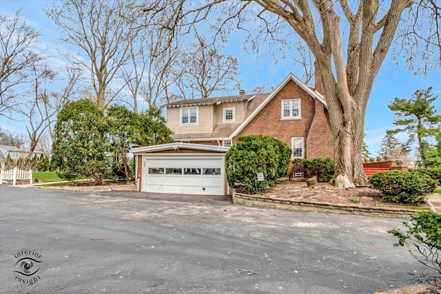 traditional-style house featuring brick siding, asphalt driveway, and fence