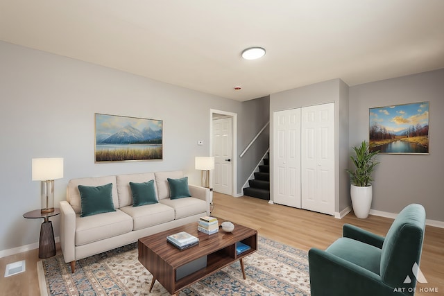 living room featuring baseboards, stairway, visible vents, and light wood-style floors