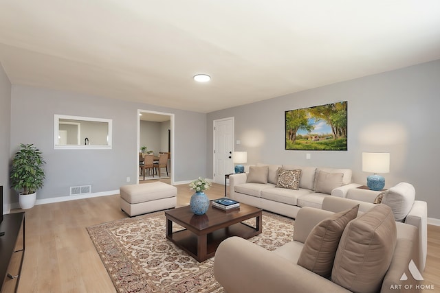 living area featuring baseboards, light wood finished floors, and visible vents