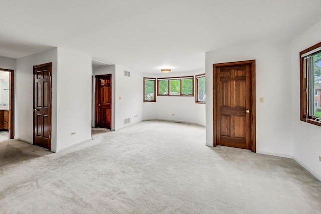 unfurnished room featuring light colored carpet, visible vents, and baseboards