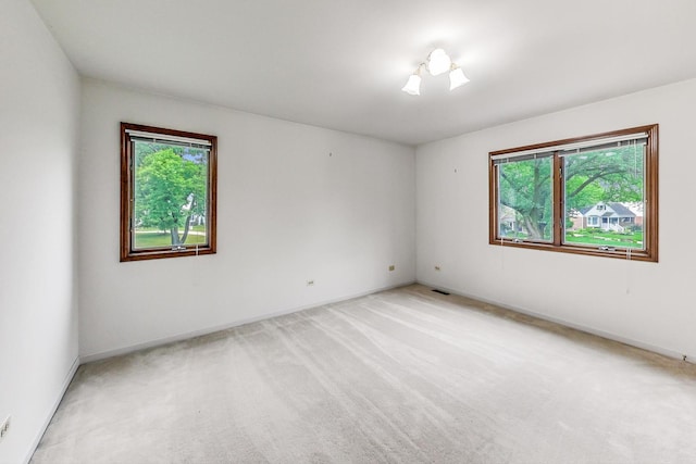 spare room with light carpet, baseboards, and visible vents