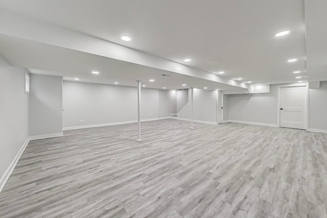 finished below grade area with baseboards, recessed lighting, and light wood-type flooring