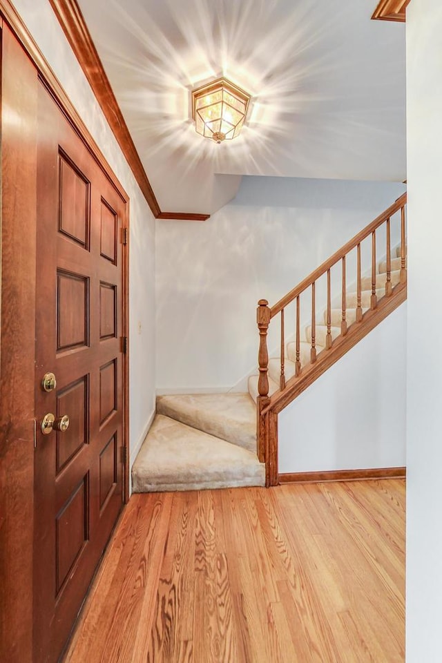 foyer entrance featuring ornamental molding, baseboards, stairway, and wood finished floors